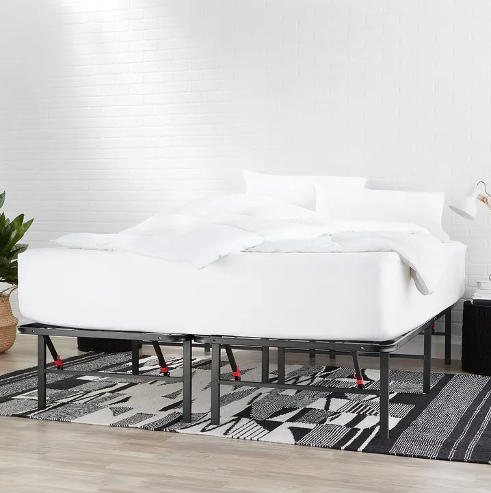 A black metal platform bed frame, staged with a white mattress and white bedding on a patterned rug