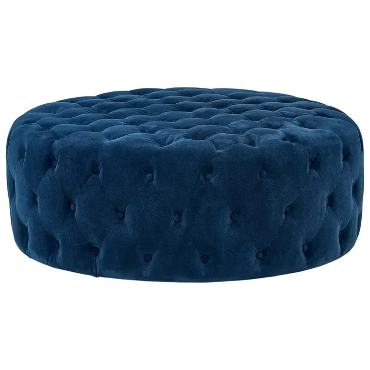 A round, button-tufted ottoman in blue velvet